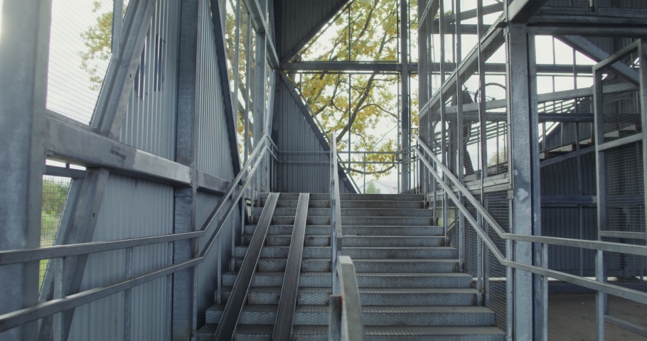 A young man of European appearance carries a bicycle down a metal ladder, hanged it on his shoulder