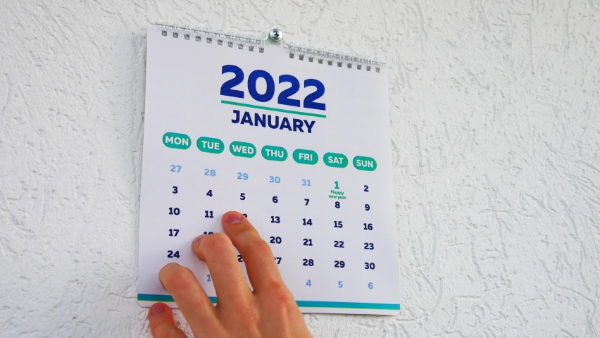 Close-up of male hands tearing off the December page of 2021 wall calendar followed by the January page of a new 2022 calendar | Shutterstock HD Video #1081272566