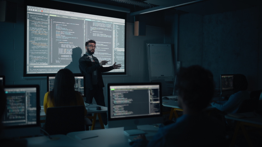 Teacher Giving Computer Science Lecture to Diverse Multiethnic Group of Female and Male Students in Dark College Room. Projecting Slideshow with Programming Code. Explaining Information Technology.