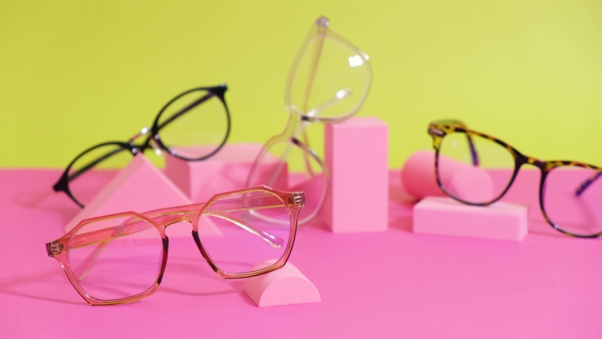 Multiple eyeglasses on a pink ang yellow background, geometric stands, trendy eyeglass frames | Shutterstock HD Video #1081286330