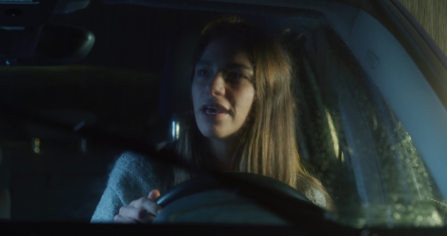 Portrait of a Young Woman Driving a Car on a Rainy Night. Female Driver Singing, Being Cautious, Following the Rules, Prioritizing Safety Over Speed, Checking the Rear Mirrors While Having Fun