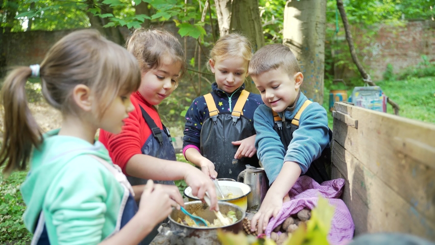 Forest kindergarten Happy Preschool or school group children play Cook in swamp improvised kitchen. Outdoors small child have fun playing. Summer Camp, kid leisure educational entertainment in nature | Shutterstock HD Video #1081289987