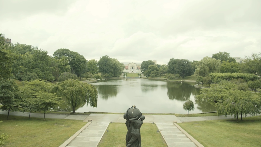 A park with a statue and a small pond in Cleveland, Ohio, USA. Dense forests of green trees for the whole family to walk.