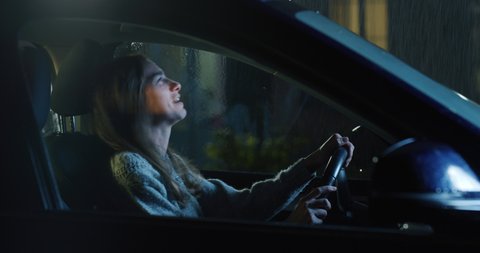 Cinematic shot of frustrated angry woman is screaming in anger, gesturing with hands and shouting alone on driver's seat of her car after traffic violation accident while while waiting car assistance.