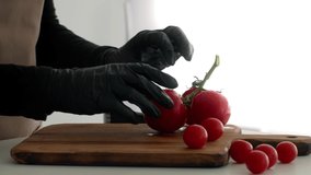 Unrecognizable Cook Cutting Red Tomatoes On Wooden Board Wearing Black Rubber Gloves Cooking In Kitchen Indoors. Cropped Shot, Closeup Of Chef's Hands. Vegetables Recipes, Food And Nutrition