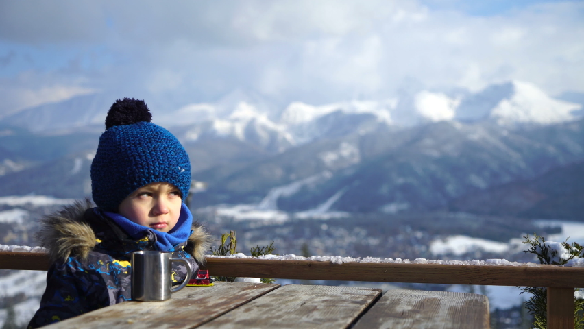 Little boy drinking hot tea in the mountains 