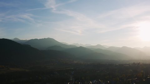 Aerial view flight over highland village lit with soft evening sun light. Drone shot beautiful mountain valley in warm sunset light. Picturesque landscape. Tatras mountains in Poland, Zakopane