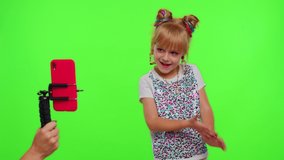 Cheerful funny little teen girl kid dancing at camera filming video using phone at home on Chroma Key background. Schoolgirl child creating her trendy content on a mobile app to share on social media