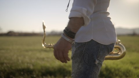 Caucasian saxophonist walks outdoors with sun flare, musician life concept. Epic cinematic shot in 4k