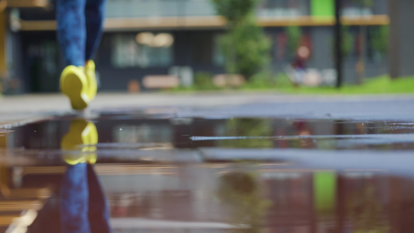 Female sports woman jogging outdoors, stepping into puddle. Single runner running in rain, making splash. Slow motion