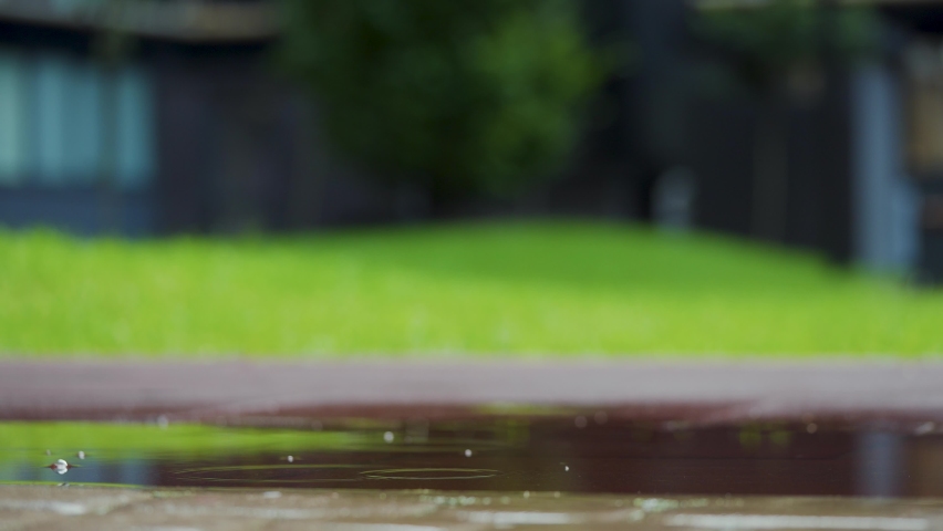 Female sports woman jogging outdoors, stepping into puddle. Single runner running in rain, making splash. Slow motion