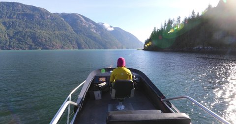 Woman Driving Motor Boat in Fjord Nature Landscape, British Columbia Near Bute, Toba Inlet, Strathcona, Campbell River. Whale Watching, Bear Viewing, Salmon Fishing Tourist Travel Destination, Canada