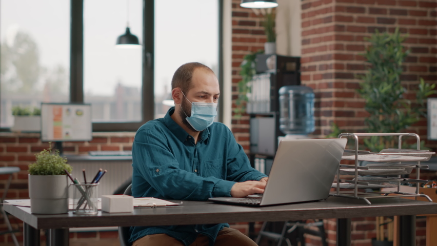 Business man greeting woman with elbow during covid 19 pandemic in startup office. Entrepreneur working with laptop while wearing face mask and talking to colleague. People at work Royalty-Free Stock Footage #1081303805