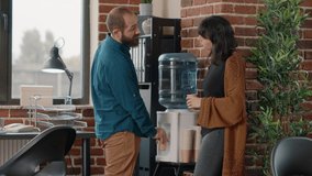 Colleagues meeting on break while having refreshment from water cooler in startup office. Man and woman having discussion while drinking fresh water for hydration from dispenser. - Powered by Shutterstock - Get 15% off with code: PIKWIZARD15