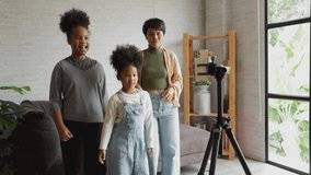 African American family have fun on holiday at home. Parents and children making dancing video for social media. Together they create new content online.