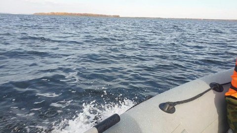 pvc boat with outboard motor floats on the pond in autumn, trolling fishing