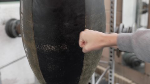This POV video shows hands punching an old, worn heavy punching bag during training.