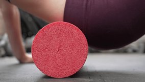 This close up video shows a red foam roller being used on a back at a gym.