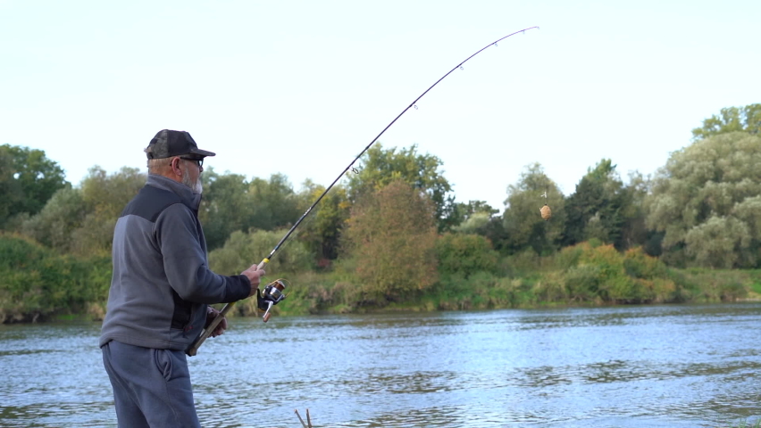 Mature man casts a fishing rod while standing on the river bank. Fishing with a spinning rod