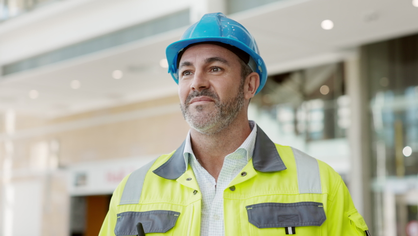 Portrait of mid adult man architect wearing blue hardhat and uniform at construction site. Successful senior construction manager in uniform and helmet smiling looking at camera. Royalty-Free Stock Footage #1081307774
