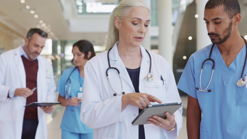 Mature woman physician discussing about medical report with young indian man nurse. Middle eastern nurse consulting senior doctor with patient details in hospital using digital tablet. Royalty-Free Stock Footage #1081307825