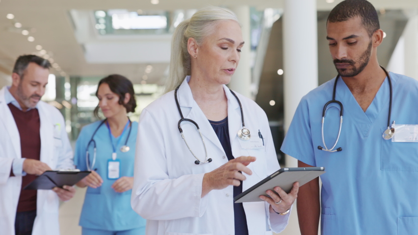 Mature woman physician discussing about medical report with young indian man nurse. Middle eastern nurse consulting senior doctor with patient details in hospital using digital tablet. | Shutterstock HD Video #1081307825