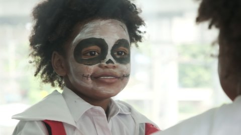 Halloween day,Black boy with zombie makeup is looking in the mirror and cheeky dancing in front of the mirror.African american child decorated dracula for party,slow motion shot.