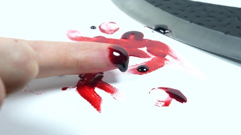 Man cut her finger with a knife. Finger with blood. Red Bloody fingerprints on the white background. Horror and crime scene concept. Halloween postcard.
