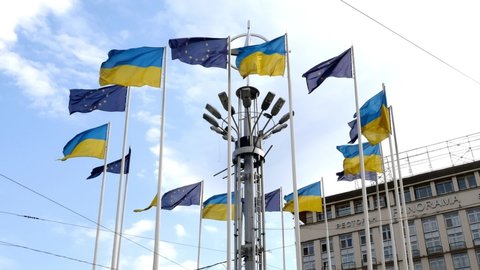 Kiev, Ukraine, July 2021: - European square in Kiev, flag poles with flag of Europe union and Ukraine fluttering against blue sky on city square. Close-up.