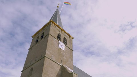 An old Gothic church in The Netherlands. The small village Boksum in Friesland is waving the rainbow flag during coming out day in 2021.