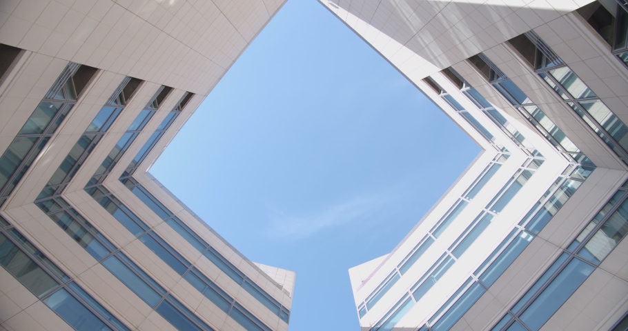 beautiful bottom view of an office building against the background of the blue sky and the plane. facade of an office building made of light concrete and glass Royalty-Free Stock Footage #1081324538