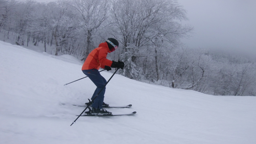 Skier Skiing Downhill on Ski Slope. Woman on ski going downhill having fun on the trails on a snowy day - People doing winter sport activities | Shutterstock HD Video #1081330682