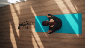 Slender woman in a sports overalls is broadcasting a workout online by filming a video on her phone. Remote work concept. Top view. Vertical video.