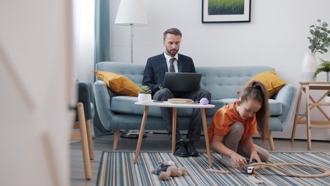 Man in suit is working at home talking on mobile phone developing business while child is chatting playing game bothering dad with toys