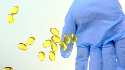 yellow capsule with fish oil in gelatin, vitamins, oil falling on the table from above, bouncing, scattering, slow motion, concept of hair care, development, production, sale of medicines, vitamins