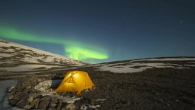 Night Starry Sky and Green Northern Lights over Glowing Yellow Tent in Khibiny Mountains at Winter Night. Russia. Time Lapse - Powered by Shutterstock - Get 15% off with code: PIKWIZARD15