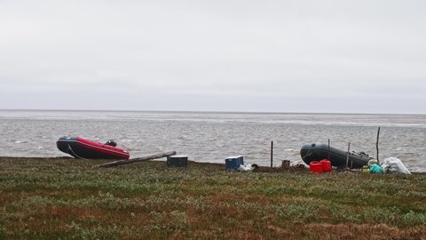 YAMAL PENINSULA - RUSSIA: CIRCA JUNE, 2021: View of boats and equipment of research expedition. Landswell line of Kara sea. Strong wind is making intensive waves that go on shore.