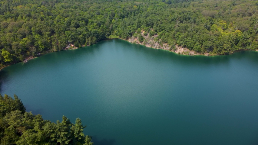 An aerial view of calm Pink lake surrounded by forested mountains in Ottawa, Ontario, Canada in 4K