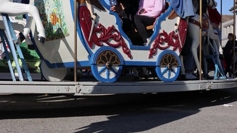 Zurich, Switzerland - October 24, 2021: Children's carousel with horses and waiting parent on a sunny day. Bottom view.