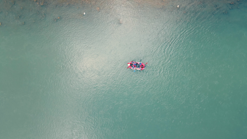 Aerial view on top from above on a boat with people floating on the river. A group of athletes sails on a red inflatable boat by the river.