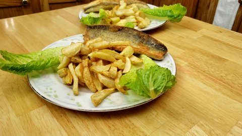 Home cooking - Rotating around serving of cooked walleye or Yellow Pike fillet and fried French fries served on lettuce as decoration and on large plate.