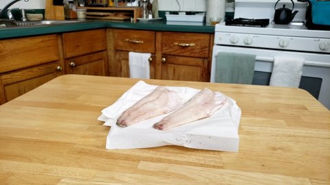 Home cooking - Checking and showing two frozen walleye or Yellow Pike fillets ready to be thawed on paper.