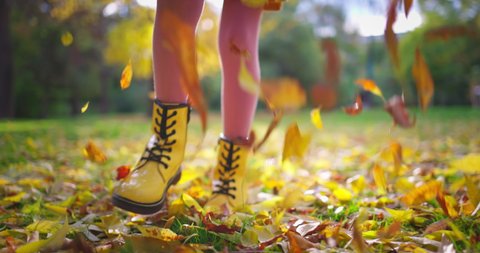 Girl legs walking on fallen leaves in autumn park. Running woman outdoor.