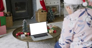 Senior caucasian woman in santa hat making laptop christmas video call, copy space on screen. christmas, festivity and communication technology.