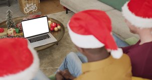 Diverse friends in santa hats making laptop christmas video call, with copy space on screen. christmas, festivity and communication technology.
