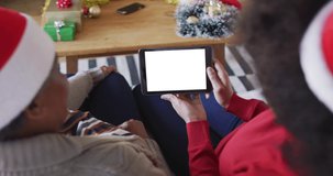 African american mother with daughter making tablet christmas video call, copy space on screen. christmas, festivity and communication technology.