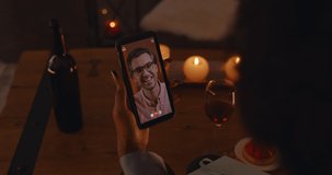 View from shoulder of african american woman holding modern smartphone and talking with caucasian man during video call. Happy multiracial couple enjoying online dating while staying at home.