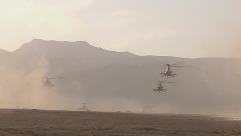 A combat unit of military helicopters flies over the desert and goes to land in the mountains. Concept: attack and reconnaissance from the air, combat operations in the zone of military conflict 3.