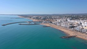 Drone footage, shooting the tourist town of Quareira, on the shores of the Atlantic Ocean, beaches with tourists. Portugal, Algarve.