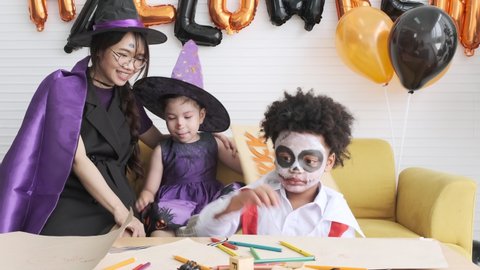 Young mother, daughter and son in witches and vampire costume playing in halloween party.